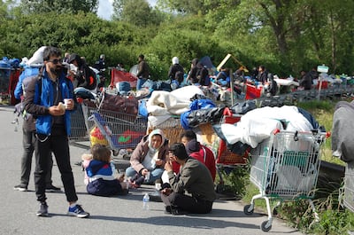 Migrants sit on the road during the evacuation of a migrant camp in northern France. AFP