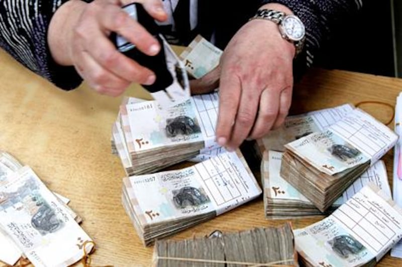 GENERIC CAPTION //// An employee stamps stacks of Syrian pound notes at the Syrian central bank in Damascus April 23, 2013. Picture taken April 23, 2013.        To match SYRIA-CURRENCY/        REUTERS/Khaled al-Hariri (SYRIA - Tags: POLITICS CONFLICT BUSINESS) - RTXYYC3