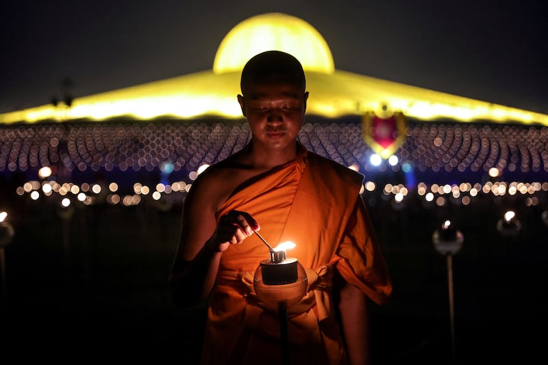 A Buddhist monk lights up a candle light at the Wat Phra Dhammakaya temple during a ceremony commemorating Makha Bucha Day in Pathum Thani province outside Bangkok, Thailand, March 6, 2023.  REUTERS / Athit Perawongmetha     TPX IMAGES OF THE DAY