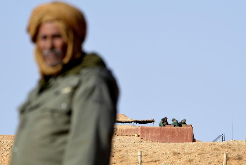 (FILES) A file photo taken on February 3, 2017 a Saharawi man standing in the Al-Mahbes area near Moroccan soldiers guarding the wall separating the Polisario controlled Western Sahara from Morocco.  A UN envoy is set to host an "initial round-table" in Geneva the first week of December 2018, between Morocco and the Polisario Front in a bid to kick-start dialogue on the disputed Western Sahara region. - TO GO WITH AFP STORY BY AMAL BELALLOUFI
 / AFP / STRINGER / TO GO WITH AFP STORY BY AMAL BELALLOUFI
