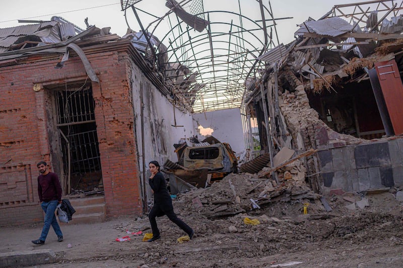 Local residents walk in a street after it was hit by a missile in Gandja, Azerbaijan, on October 8, 2020, near the disputed Nagorno-Karabakh province's capital Stepanakert as fighting between Armenian and Azerbaijani forces spilled over ahead of a first meeting of international mediators in Geneva. Armenia accused Azerbaijan on October 8, 2020, of shelling a historic cathedral in Nagorno-Karabakh while international mediators seeking to halt escalating fighting over the disputed region were expected to meet in Geneva. / AFP / BULENT KILIC
