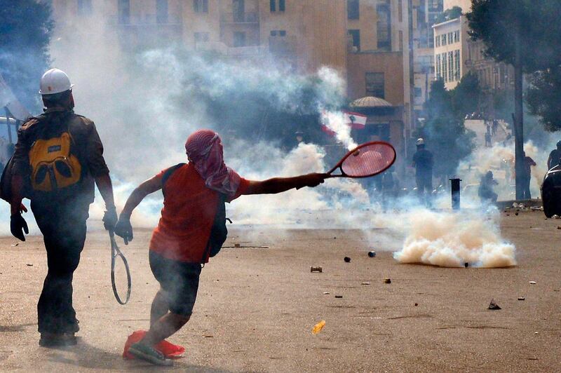 An anti-government protester uses a tennis racket to return a tear gas canister at riot police. EPA