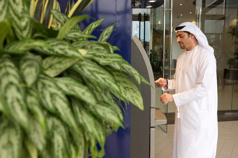 An arab man using an ATM Machine.