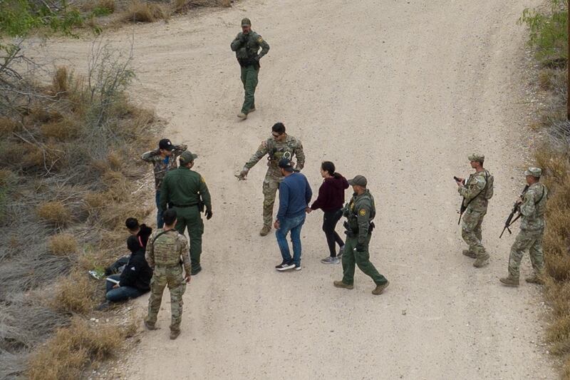 US border patrol agents and National Guard soldiers detain migrants in La Joya, Texas. Reuters