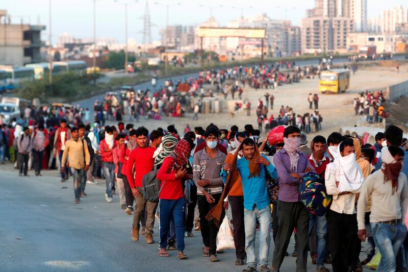 Migrant workers walk towards a bus station along a highway with their families as they return to their villages, during a 21-day nationwide lockdown to limit the spreading of coronavirus disease (COVID-19), in Ghaziabad, on the outskirts of New Delhi. REUTERS