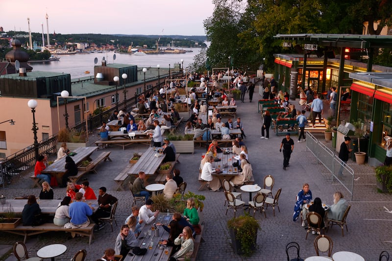 People sit outdoors at a restaurant in Stockholm, Sweden. On July 1, Sweden eased Covid-19 restrictions, including allowing diners to stay longer at eateries.