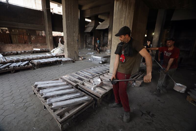 Workers pour aluminum prepared of recycled material at a workshop.