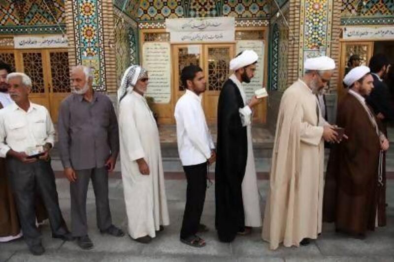 Men stand in line to vote during the Iranian presidential election at a mosque in Qom, south of Tehran on Friday.