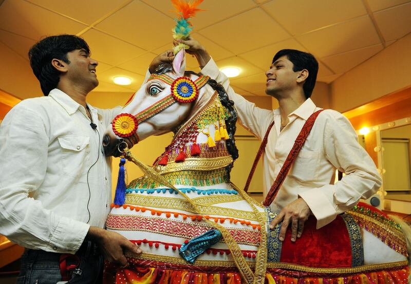 Sayed Faisal (on left) and Neeraj Ruparel (on right), wardrobe props managers, The Merchants of Bollywood, add finishing touches to a prop horse that is used during the performance of show. 