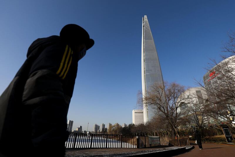 A man walks along a path as the Lotte World Tower, which houses the Lotte Group headquarters, stands in Seoul, South Korea, on Tuesday, Feb. 13, 2018. The Seoul Central District Court is scheduled to issue a ruling on Lotte Group Chairman Shin Dong-bin over bribery charges relating to a 7 billion won ($6.5 million) donation to a sports foundation controlled by Choi Soon-sil, a confidante of former South Korean President Park Geun-hye. Photographer: SeongJoon Cho/Bloomberg