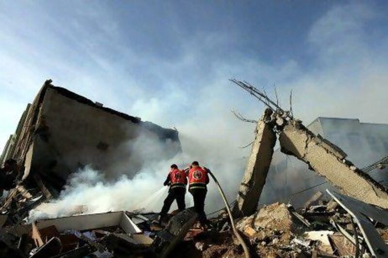 Palestinian firefighters try to extinguish a fire in a destroyed Hamas Ministry of Interior building after an Israeli air strike in Gaza City on Friday.