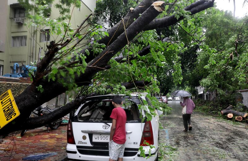 An Indian boy inspects a damaged car in Kolkata after Cyclone Remal made landfall on Sunday. EPA