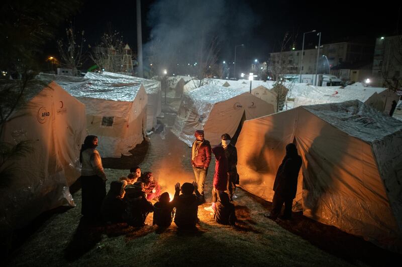 Earthquake survivors spend the night as they sit around a fire  near a makeshift tent in a park in Sivrice, Turkey. Getty Images