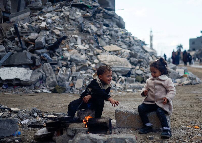 Palestinian children sit by the fire next to the rubble of a house hit in an Israeli strike in Khan Younis, southern Gaza Strip. Reuters