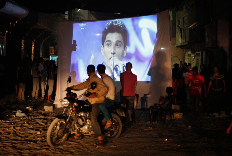 People watch Palestinian singer Mohammed Assaf as he sings in Beirut during the "Arab Idol" program, in Khan Younis in the southern Gaza Strip June 22, 2013. The 22-year-old singer Mohammed Assaf, from the Gaza Strip, was named the winner of "Arab Idol" in a TV talent contest in Beirut.  REUTERS/Ibraheem Abu Mustafa (GAZA - Tags: SOCIETY ENTERTAINMENT) *** Local Caption ***  GAZ04_PALESTINIANS-_0622_11.JPG