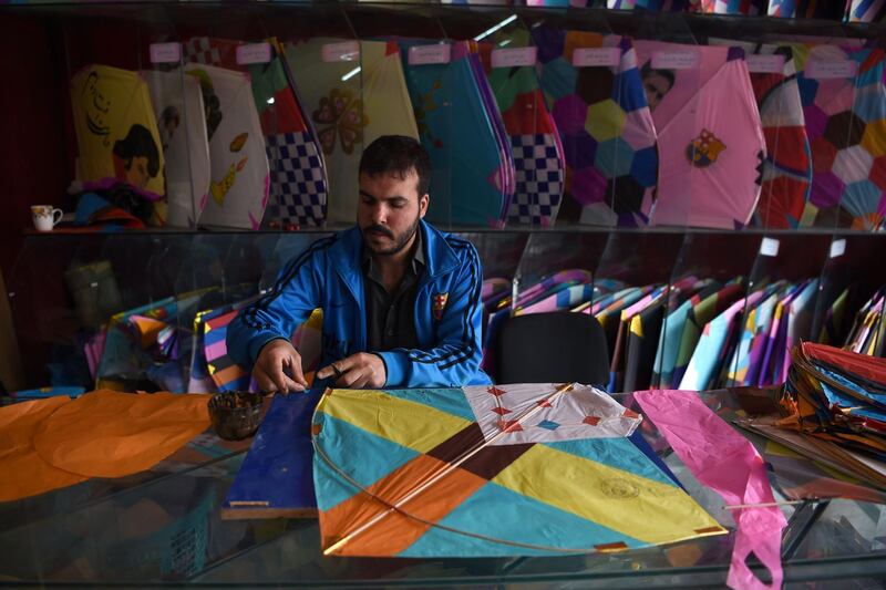 A kite vendor cuts tissue paper as he makes a kite in a shop in Shor Bazaar in Kabul.