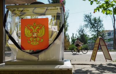 A man cycles past a ballot box with the coat of arms of Russia during early voting for the local elections in Mariupol in Russian-controlled Ukraine. EPA
