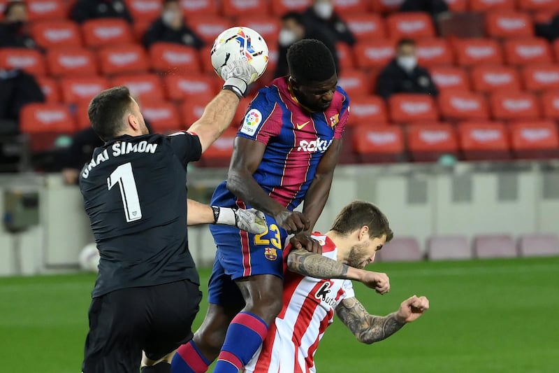 (FromL) Athletic Bilbao's Spanish goalkeeper Unai Simon, Barcelona's French defender Samuel Umtiti and Athletic Bilbao's Spanish defender Inigo Martinez jump for the ball during the Spanish league football match FC Barcelona against Athletic Club Bilbao at the Camp Nou stadium in Barcelona on January 31, 2021. (Photo by LLUIS GENE / AFP)
