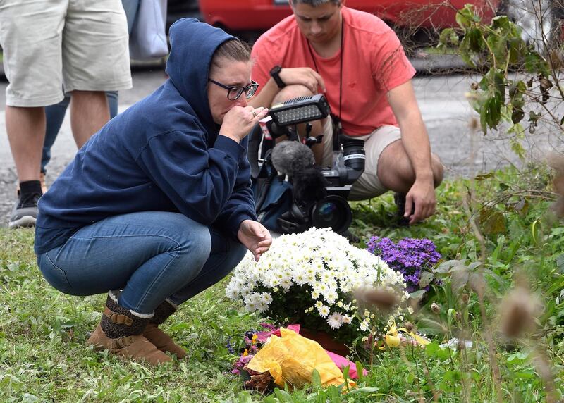 A woman kneels after placing flowers. AP Photo
