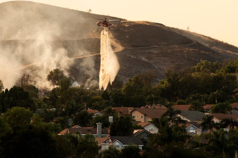 A helicopter makes water drops over the Blue Edge Fire as firefighters work at controlling its spread by lighting back fires near homes in Butterfield Ranch, Orange County, South of Los Angeles, California.  EPA