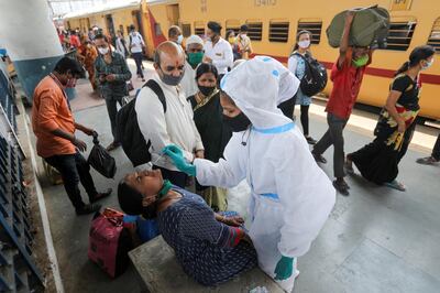 A health worker in personal protective equipment (PPE) collects a swab sample from a woman during a rapid antigen testing campaign for the coronavirus disease (COVID-19), at a railway station platform in Mumbai, India, March 17, 2021. REUTERS/Francis Mascarenhas