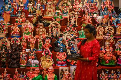 A woman picks up an idol representing deities and characters from Hindu mythology, used as a decoration ahead of the Navratri festival, in Chennai. AFP