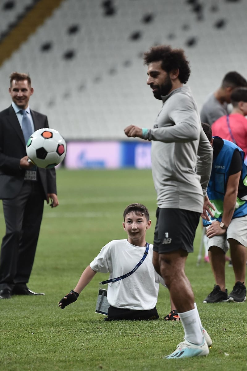 Liverpool's Egyptian midfielder Mohamed Salah plays football with a child at the end of a training session. AFP