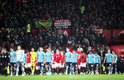 Manchester United fans wave banners saying 'Glazers Out' as the two teams walk out on to the pitch before the Carabao Cup fourth round match at Old Trafford, Manchester. PA