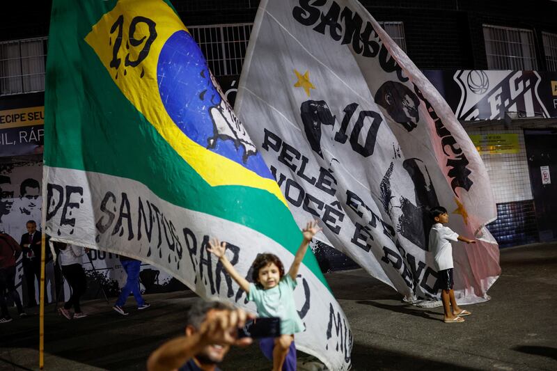 Fans wave flags to mourn the death of Pele in Santos. Reuters