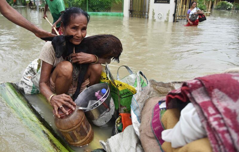 A woman clings on to her goat while sitting on a raft in Koliabor. Biju Boro / AFP Photo