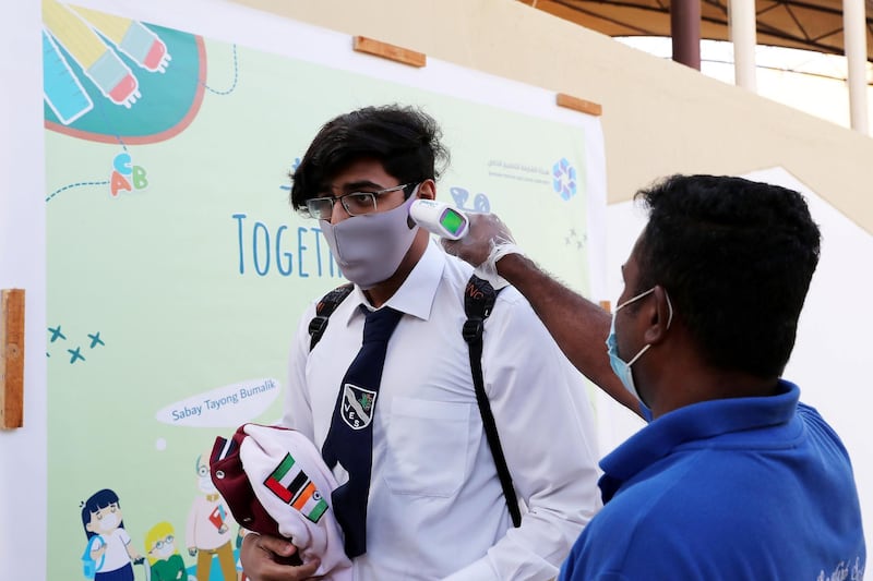 SHARJAH, UNITED ARAB EMIRATES , September 28 – 2020 :- Staff member checking the temperature of the student at the entrance gate on the first day of the school after reopening at the Victoria English School in Sharjah. New Covid safety setup placed in different areas of the school such as hand sanitizer, safety message, social distancing stickers pasted on the floor, disinfection tunnels installed at all the gates of the school. (Pawan Singh / The National) For News. Story by Salam
