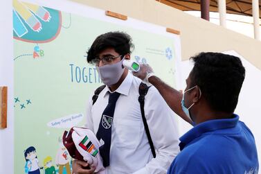 Staff member checking the temperature of the student at the entrance gate on the first day of the school after reopening at the Victoria English School in Sharjah. Pawan Singh / The National