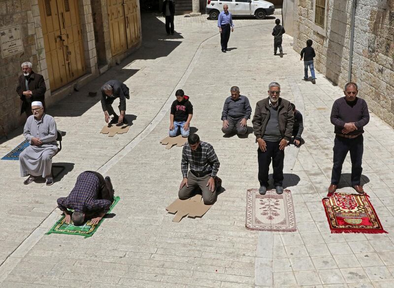 Palestinian men perform the second Friday prayer of the Muslim holy month of Ramadan on the street outside of the closed-down Al-Qazazin mosque in the old town of the West Bank city of Hebron, on May 1, 2020, amid heightened security and social distancing measures due to the COVID-19 pandemic. (Photo by HAZEM BADER / AFP)