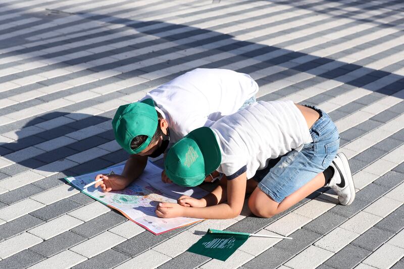 Children ing green caps – the colour of the Saudi flag – colouring in the Expo map.