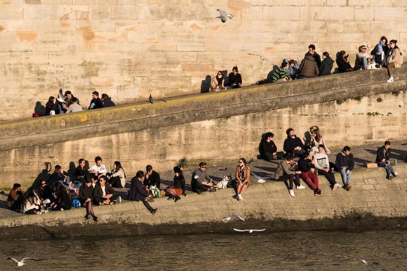 People gather on th banks of the River Seine on a sunny afternoon in Paris, France. AFP