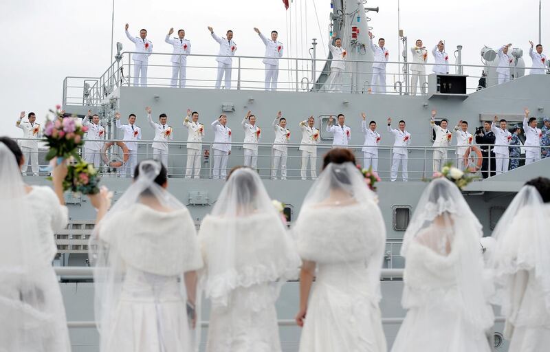 Navy personnel of People's Liberation Army (PLA) wave at their brides during a mass wedding at a military base in Zhoushan, Zhejiang province, China.  Reuters