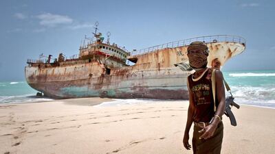 A masked Somalian pirate stands near a Taiwanese fishing vessel that washed ashore in Hobyo in 2012. A Dubai maritime security conference has heard the latest challenges facing seafarers in the region. Farah Abdi Warsameh / AP Photo