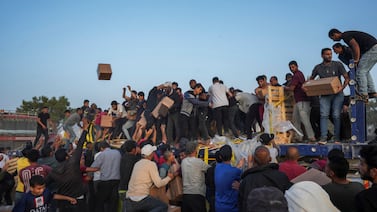 Palestinians storming lorries loaded with aid brought in via a US-built pier, in the central Gaza Strip in May. AP