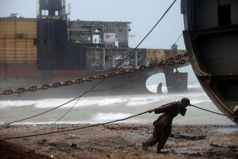 Man on a wire: a worker pulls a wire to help peel away part of the outer structure of a beached vessel.