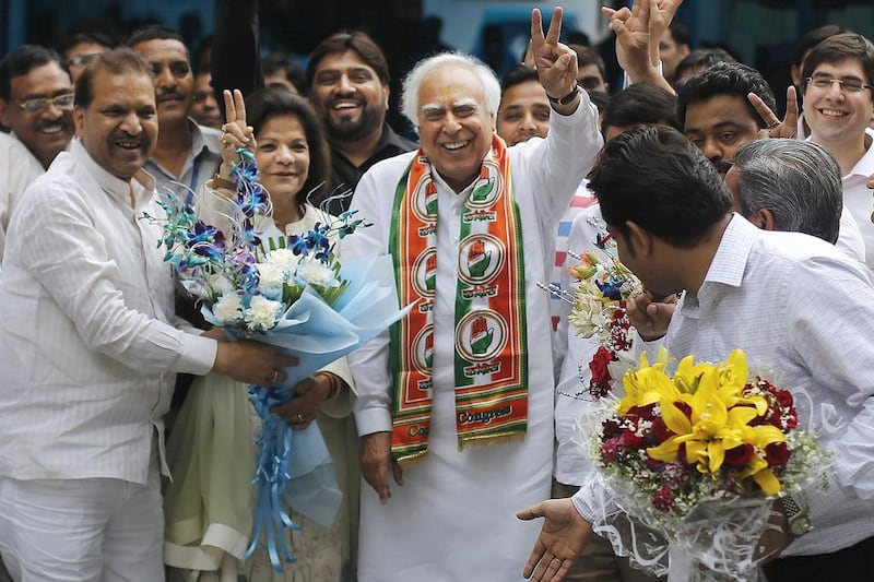 Congress party leader Kapil Sibal, centre and his wife Promila Sibal flash victory signs as supporters present them with flower bouquets after Sibal filed his nomination papers for the upcoming parliamentary elections in New Delhi, India, on Thursday, March 20, 2014. India will hold national elections from April 7 to May 12, kicking off a vote that many observers see as the most important election in more than 30 years in the world’s largest democracy. Altaf Qadri / AP Photo