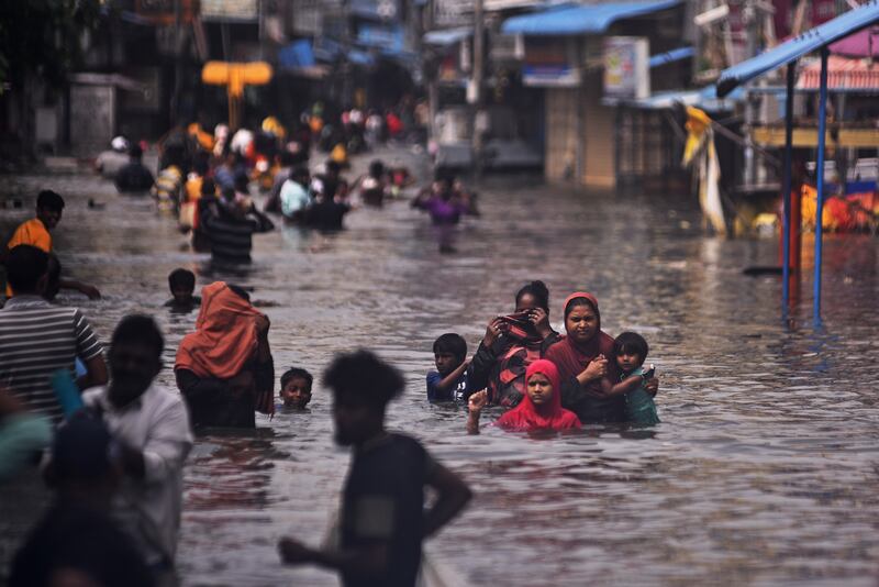 People wade through a flooded street following a heavy downpour during Cyclone Michaung, in Chennai. EPA