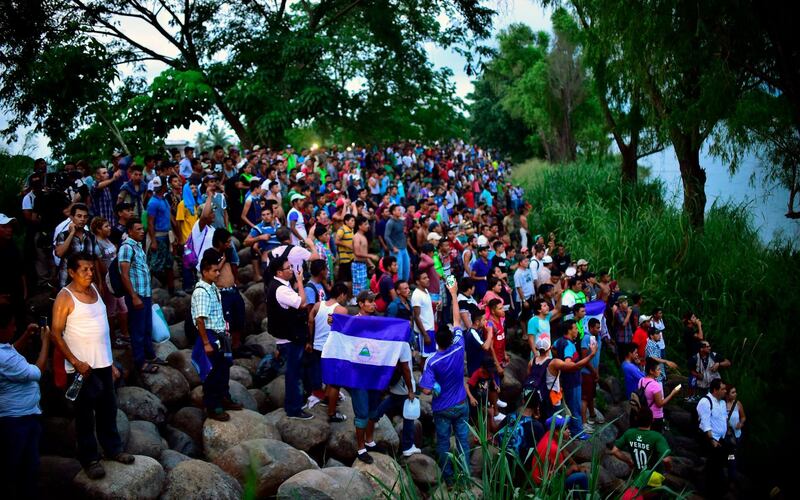 Migrants cheer at the rest who are still waiting to cross at the border. AFP