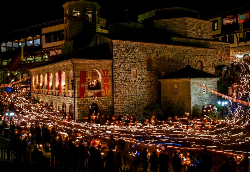 A long exposure photo shows Christian Orthodox pilgrims holding candles as they walk around the monastery of St. John the Baptist in North Macedonia. EPA