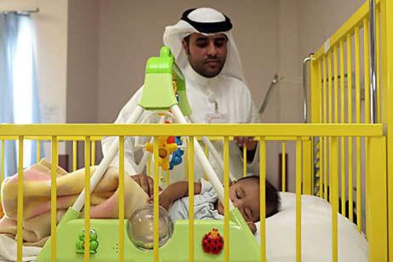 Basil Hussein, a volunteer at Al Qassimi hospital, tends to Omar.