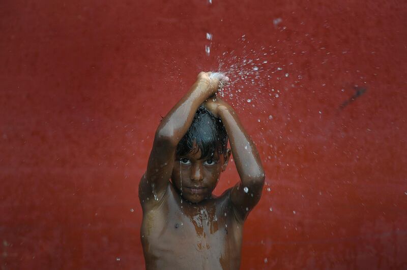 A child bathes with rain water in La Guaira, Venezuela, Sunday, July 26, 2020, amid the new coronavirus pandemic, as the remnants of Tropical Storm Gonzalo pass through the Caribbean. (AP Photo/Matias Delacroix)
