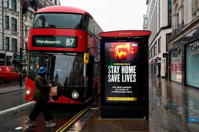 A pedestrians walks past NHS signage promoting "Stay Home, Save Lives" on a bus shelter in London on January 14, 2021 during Britain's third coronavirus lockdown. / AFP / Niklas HALLE'N
