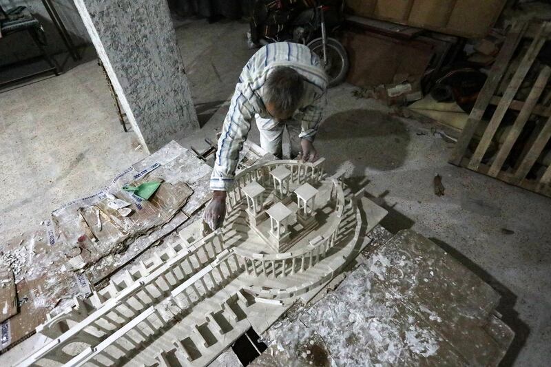 Ali Saleh, a 58-year-old displaced Syrian originally from Palmyra, builds from memory a wood and gypsum model of a prominent archaeological landmark of his home city that was heavily damaged by Islamic State (IS) militants, at a workshop home in the rebel-held city of al-Bab northwest of Aleppo in northern Syria on January 14, 2021. - Ten years of Syria's civil war have robbed Saleh of his home in the desert city, his three sons and daughter, and the last of his poor hearing, his family says. But he still vividly remembers Palmyra's ruins, where he accompanied restoration and excavation teams for 25 years, before the Islamic State group overran the city in 2015. (Photo by Bakr ALKASEM / AFP)