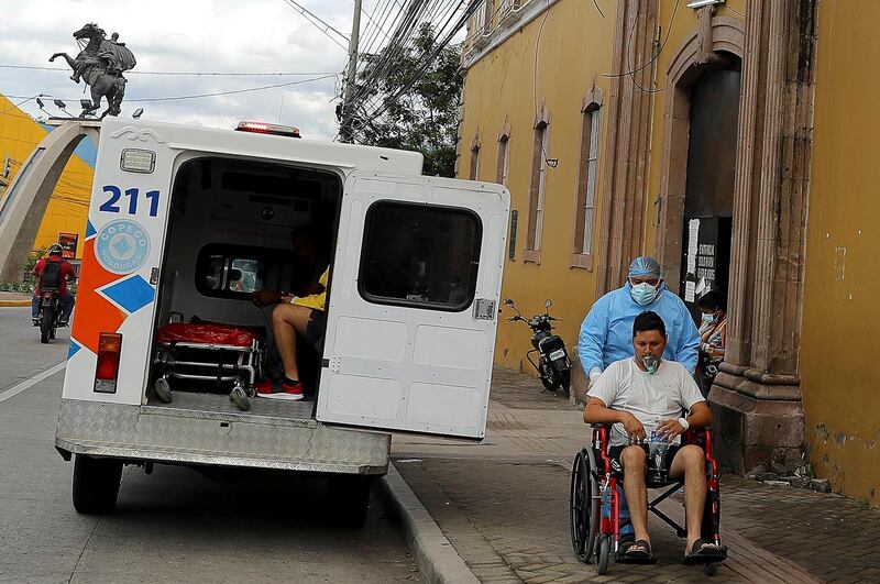 A paramedic carries a patient suspected of having Covid-19 in a wheelchair, outside the San Felipe Hospital, in Tegucigalpa, Honduras. EPA