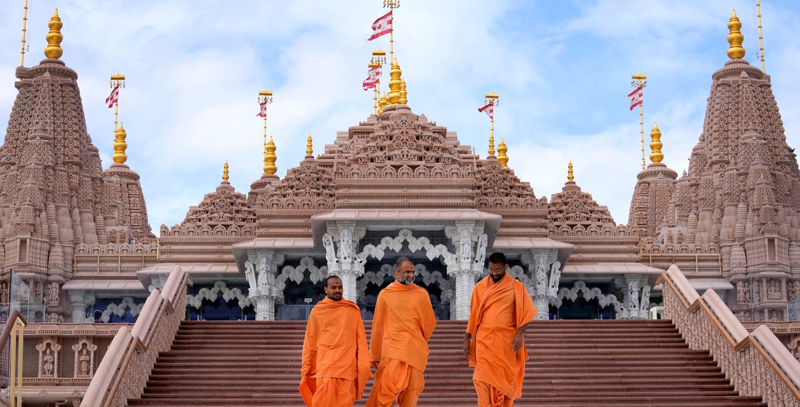 Hindu monks walk down the stairs of the first stone-built Hindu temple in Abu Mureikha, 40 kms, 25 miles, northeast of Abu Dhabi, United Arab Emirates, Monday, Feb.  12, 2024.  The soon-to-open BAPS Hindu Mandir signals just how far the United Arab Emirates has come in acknowledging the different faiths of its expatriate community, long dominated by Indians who power life across its construction sites and boardrooms.  (AP Photo / Kamran Jebreili)