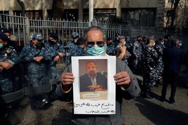 An anti-Hezbollah protester holds a picture of Lokman Slim, a longtime Shiite political activist and researcher, who has been found dead in his car, during a protest in front of the Justice Palace in BeirutBeirut, Lebanon, Thursday, Feb. 4, 2021. The Arabic words on poster read "Hezbollah's arms against who? Weapons of terrorism." (AP Photo/Bilal Hussein)